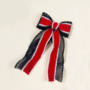 Elegant red velvet and black organza bow hair clip with plush trim on beige background