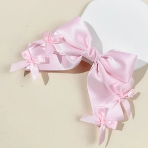 Détail d'une pince à cheveux à double nœud en satin rose avec petits nœuds ruban