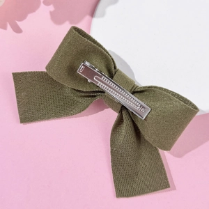 Dettaglio del fermaglio per capelli a fiocco in tessuto verde oliva con clip in metallo