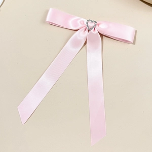 Dettaglio del fermaglio a fiocco in raso rosa con uno scintillante strass a cuore argento