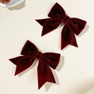 Close-up of a pair of deep wine red velvet bow hair clips with premium soft texture