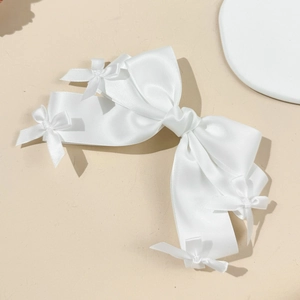 Détail d'une pince à cheveux en satin blanc élégante avec des petits nœuds décoratifs