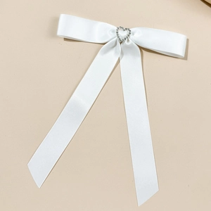 Dettaglio del fiocco in raso bianco con fibbia a cuore in strass per capelli