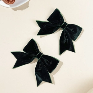 Macro detail of dark green velvet bow hair clips with soft texture and vintage style