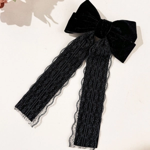 Detail of elegant black velvet hair bow with delicate lace streamers on a neutral base