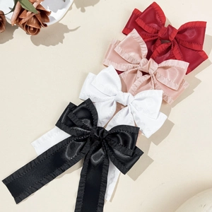 Détail de barrettes à nœuds en satin avec volants et longs rubans en quatre couleurs