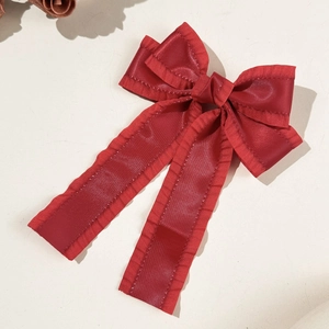 Détail de la pince à cheveux noeud rouge avec bords à volants et longs rubans satin