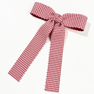 Détail de la barrette à nœud vichy rouge avec bords ondulés et longs rubans élégants