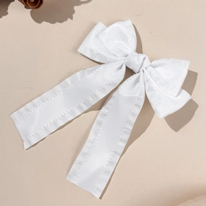 Gros plan d'une barrette à nœud en satin blanc avec rubans élégants et couture soignée