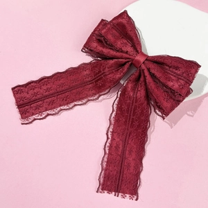 Close-up of wine red lace bow hair clip with intricate hollowed-out floral pattern edges