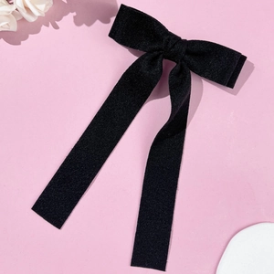 Detailed view of the elegant black velvet bow hair clip with long flowing ribbons on pink base