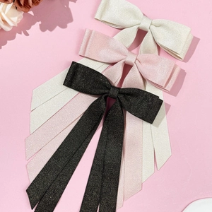 Detail of layered ribbon bow hair clips in black, pink and white with herringbone texture