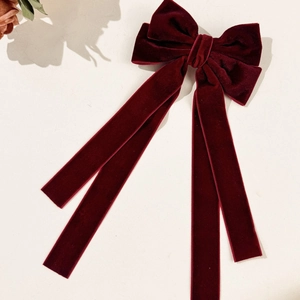 Elegant deep red velvet bow hair clip with long trailing ribbons on a minimalist background