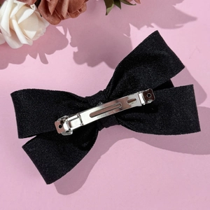 Vue détaillée d'une barrette nœud en velours noir avec clip métallique argenté gravé