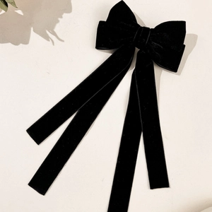 Detail of elegant black velvet bow hair clip with long ribbons and premium texture