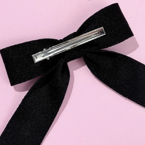 Close-up of the silver metal alligator clip mechanism on the back of the black bow hair clip