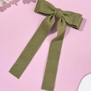 Macro detail of dark green wool hair clip showing premium fabric texture and long ribbon