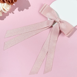 Detail view of pink herringbone ribbon bow hair clip with long flowing streamers