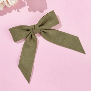 Close-up of olive green wool bow hair clip with textured matte fabric on pink background
