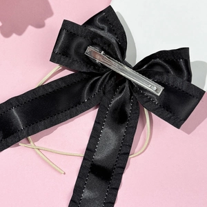 Close-up of the black satin bow hairclip showing fine stitching and metal duckbill clip