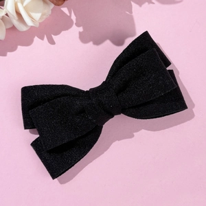 Détail de la pince à cheveux noeud en velours noir double couche sur fond rose