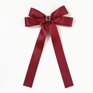 Détail d'un nœud en satin rouge foncé avec pierre de rubis et bordure en cristal