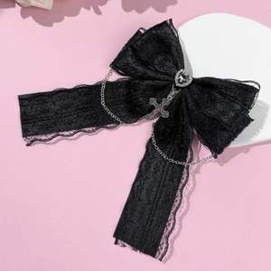 Détail d'une pince à cheveux gothique en dentelle noire avec bijou cœur et croix en métal