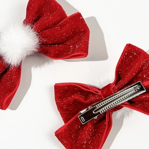 Detail view of red velvet bow hair clip with white fur pom pom and metal alligator clip