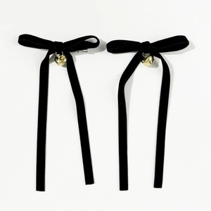 Detail of black velvet bow hair clips with golden bells and silver metal fasteners