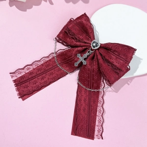 Détail d'un nœud en dentelle bordeaux gothique avec bijou cœur et pendentif croix