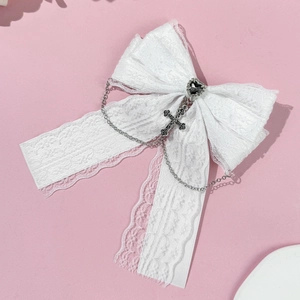 Détail du nœud en dentelle blanche avec cœur noir et pendentif croix argenté élégant