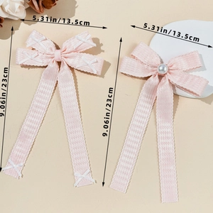 Détail de barrettes à nœuds roses avec perles et broderie à point de croix