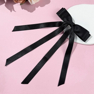 Detail of elegant black ribbon hair clip with delicate texture and long flowing streamers
