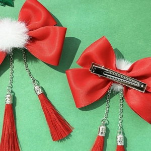 Detail of red bow hair clips with white pom poms and tassels on a festive background