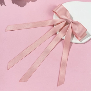 Detail of elegant pale pink satin bow hair clip with long ribbons on stone tray