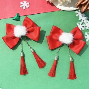 Detail of red bow hair clips with white fuzzy pom poms and long red tassels for girls