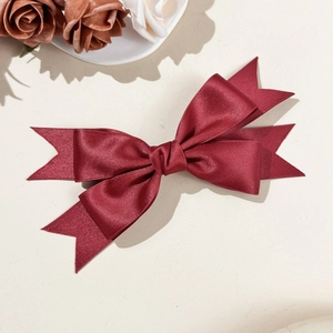Elegant wine red satin double-layer bow hair clip with a silky finish on textured background