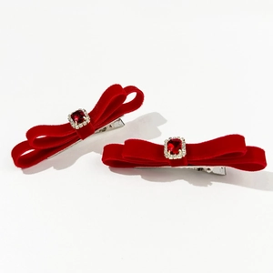 Macro detail of red velvet bow hair clips with square ruby rhinestone and silver duckbill clip