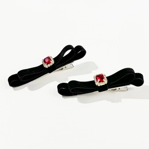 Detailed macro view of black velvet bow hair clips with red ruby and crystal accents