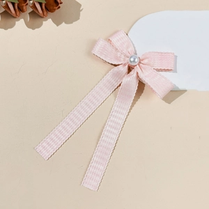 Vue détaillée du nœud rose avec motif pied-de-poule, perle et rubans longs élégants