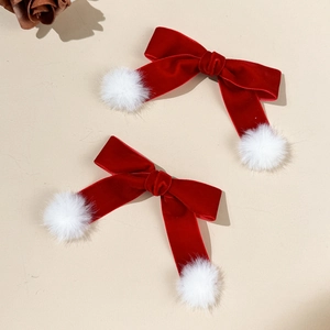Close-up of red velvet bow hair clips with soft white pom-poms for festive holiday styling