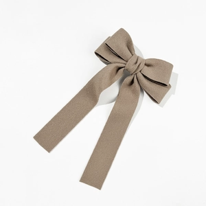 Detail view of the brown woven fabric bow hair clip with elegant long streamers