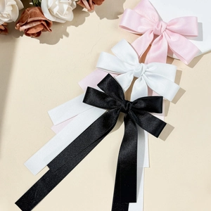 Detail view of colorful satin ribbon bow hair clips in pink, white, and black colors