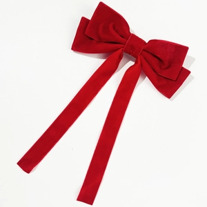 Close-up of a large red velvet bow hair clip with elegant long ribbons for styling