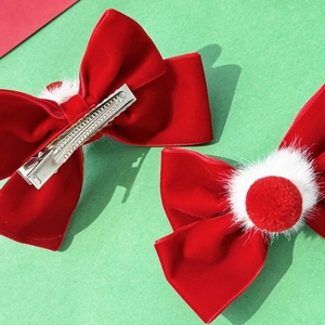 Detailed macro view of red velvet bow hair clips with soft white pom-pom decorations