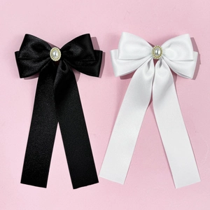 Détail de barrettes noeuds en satin avec perles et strass sur fond rose poudré