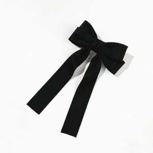 Detailed view of elegant black velvet bow hair clip with long ribbons and metal spring clasp