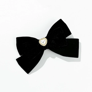 Dettaglio del fermaglio a fiocco in velluto nero con cuore di perle in stile vintage