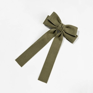 Detailed close-up of dark green velvet bow hair clip with long flowing ribbons