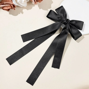 Detail of elegant black satin bow hair clip with long flowing ribbon streamers